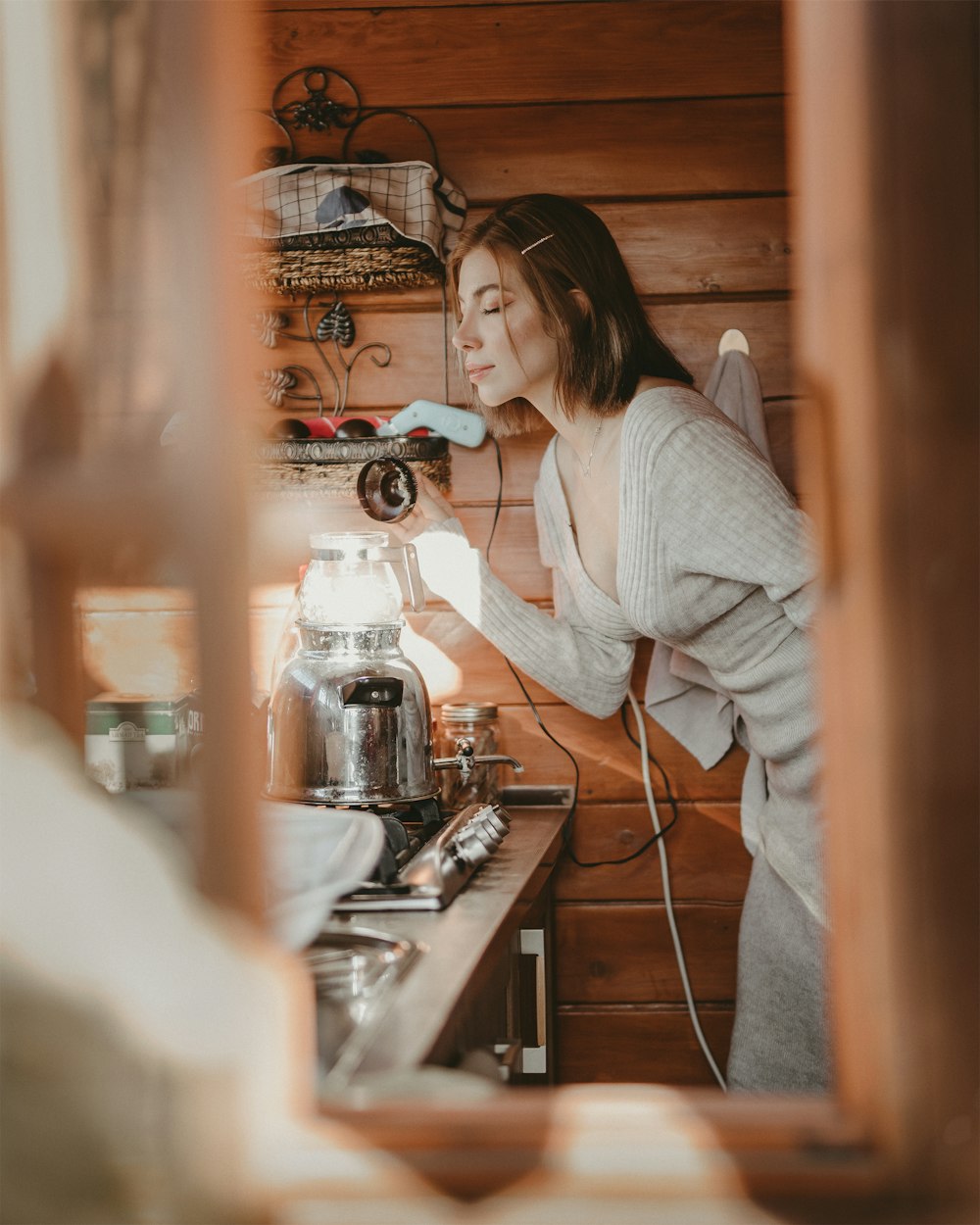 woman in gray sweater pouring coffee on white ceramic mug