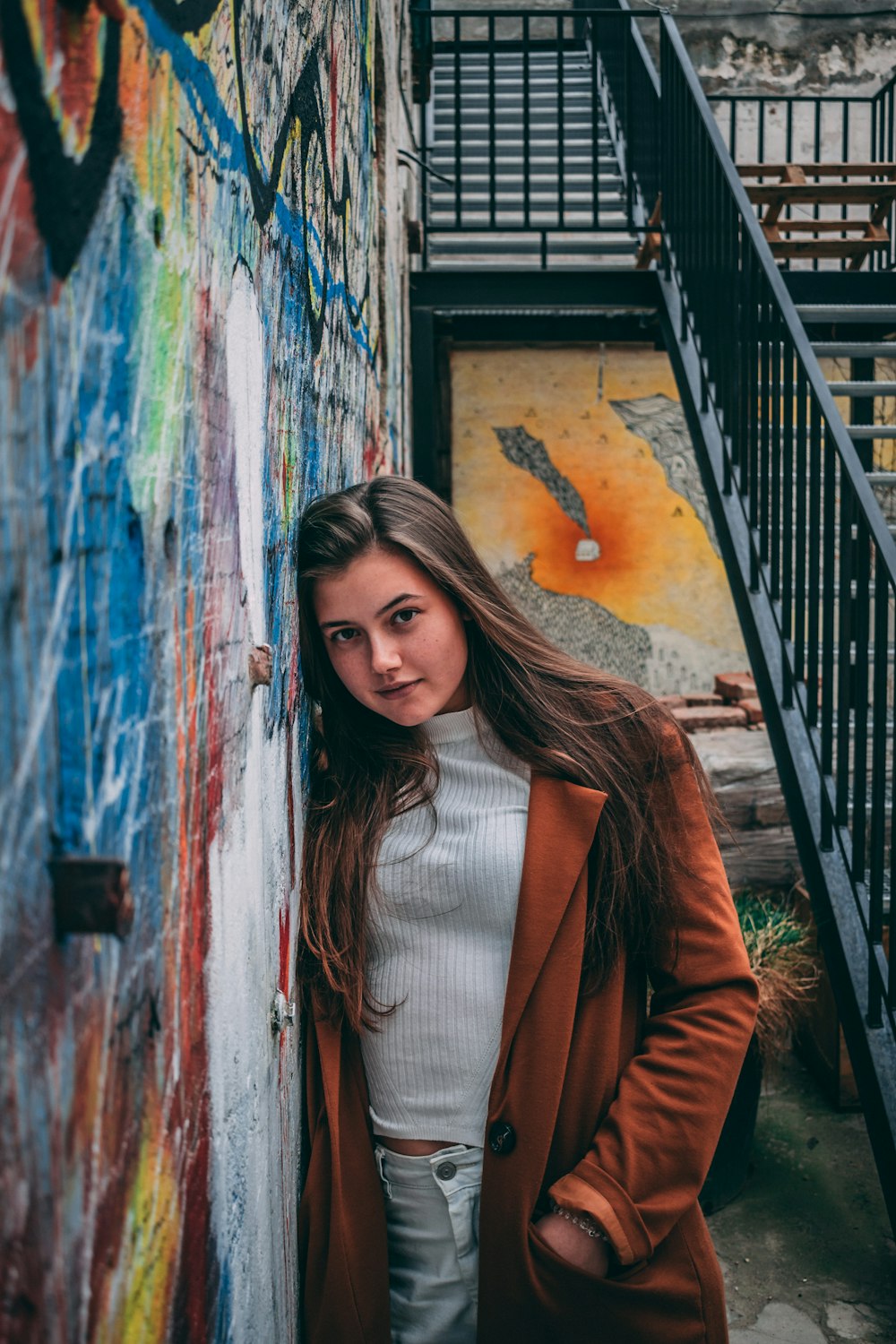 woman in brown blazer standing beside wall with graffiti