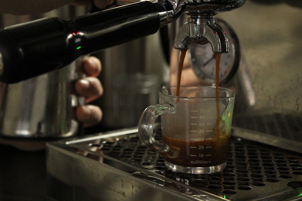 person pouring water on clear glass cup