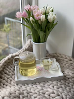 A cozy scene with a bright ceramic teapot surrounded by fresh flowers and soft linen napkins.