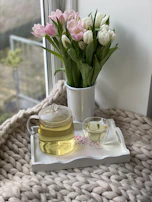 A joyful scene of a ceramic teapot surrounded by fresh flowers and a cozy linen cloth.