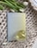 A textured, woven surface with a pastel-colored book titled 'Explore Your Inner World for Happiness & Growth' is accompanied by a glass cup filled with light-colored tea. A few white tulips with green leaves provide an elegant touch.