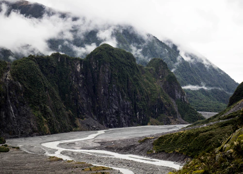 A mist-covered mountain range with a calm river winding through lush greenery.