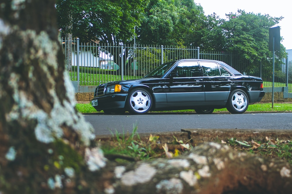 black sedan parked near green trees during daytime