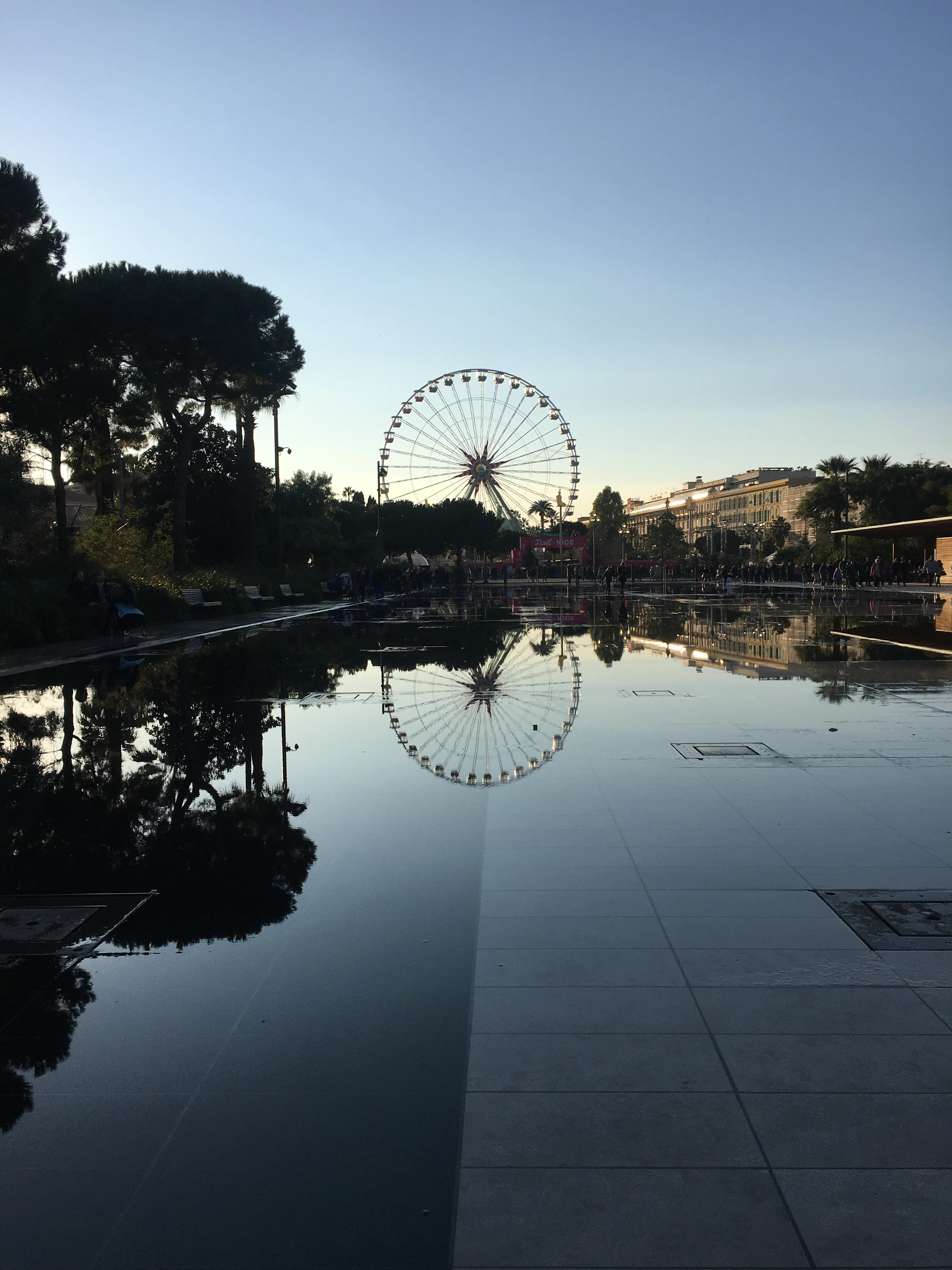 A Ferris wheel reflects in Nice's Promenade du Paillon mirror pool at dusk.