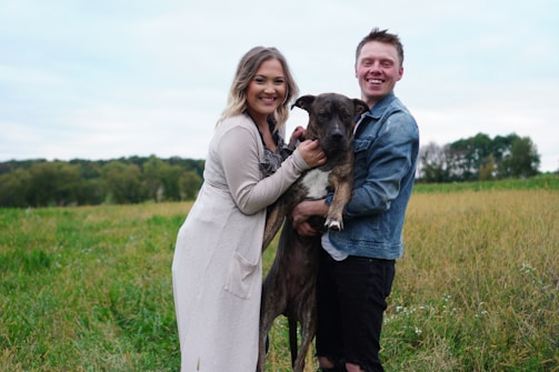 Smiling family playing with their healthy dog outdoors after vaccination.