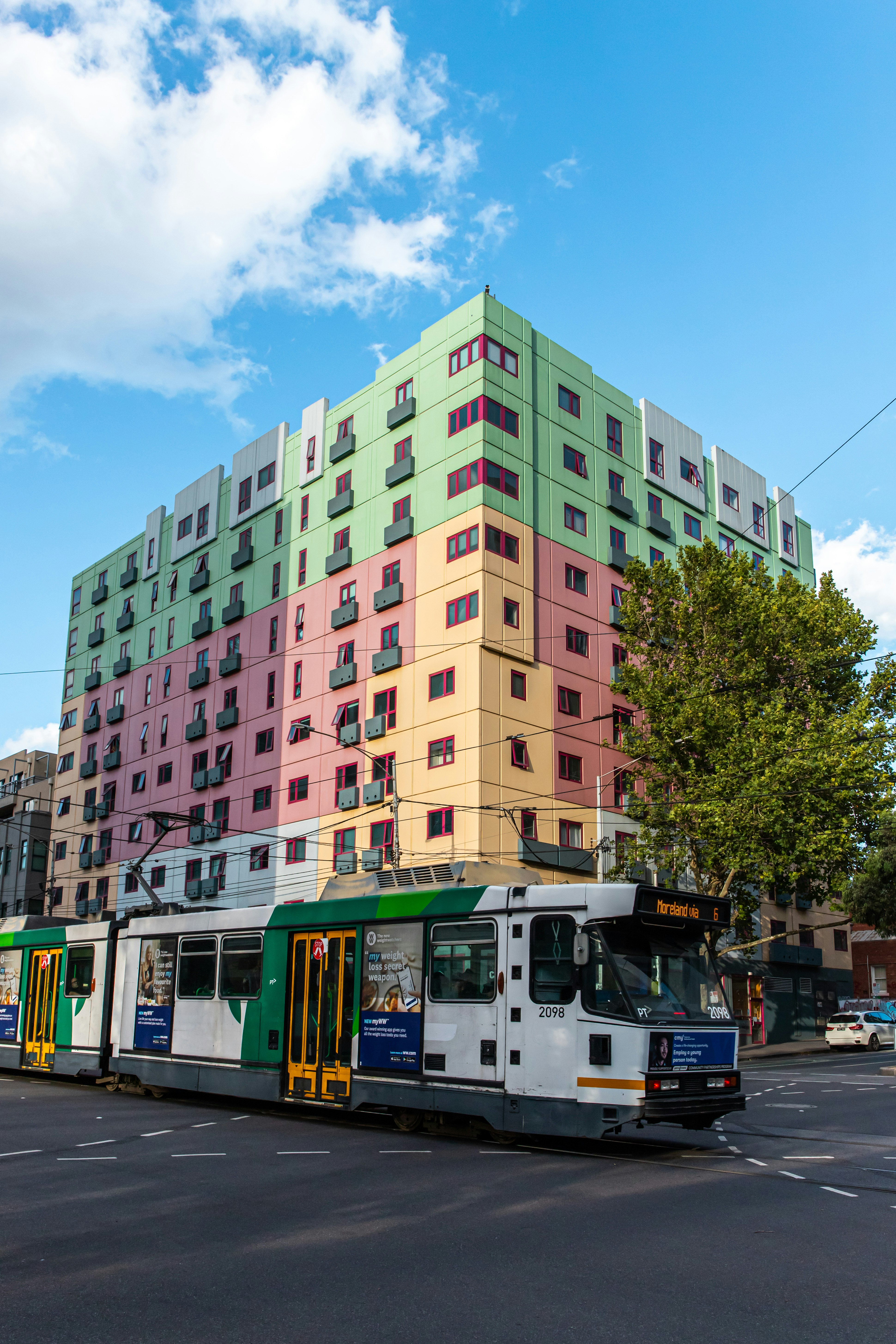 white and green bus on road near green and brown high rise building during daytime