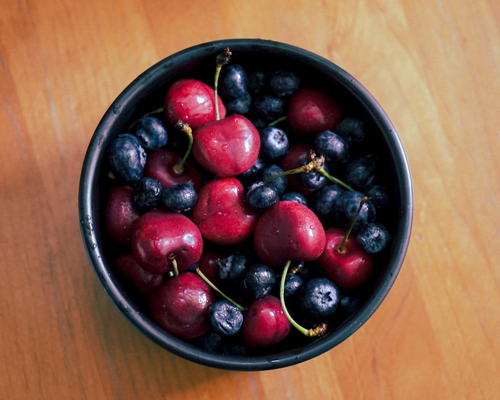 red and black berries in black ceramic bowl