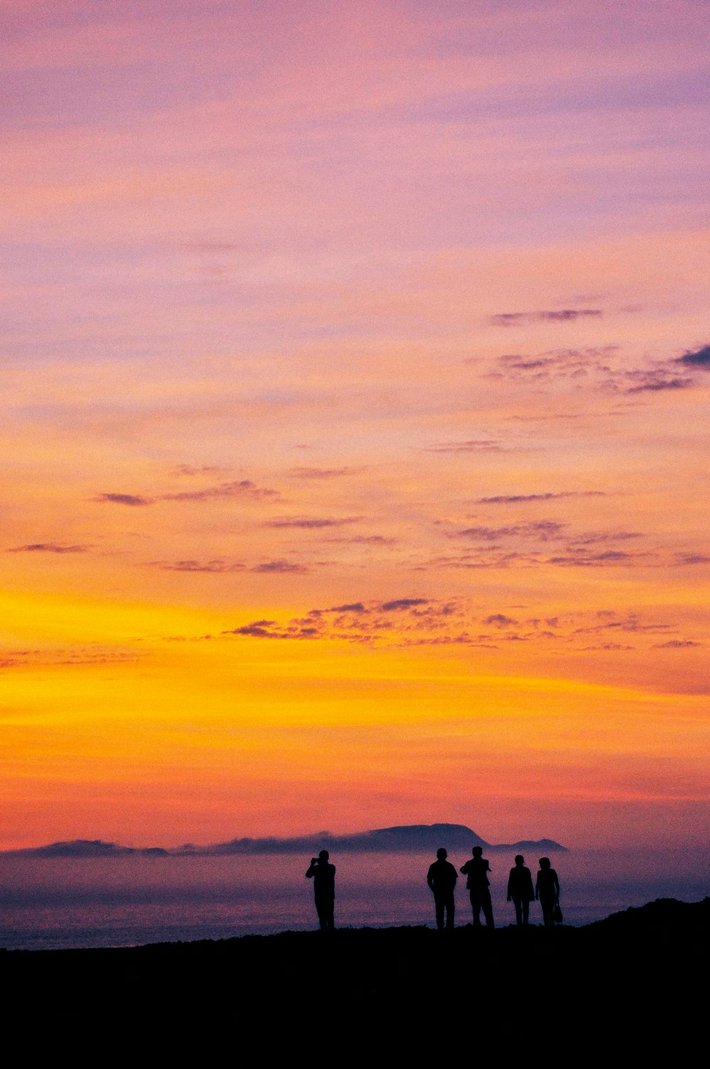 Silueta de la gente en la montaña durante la puesta del sol