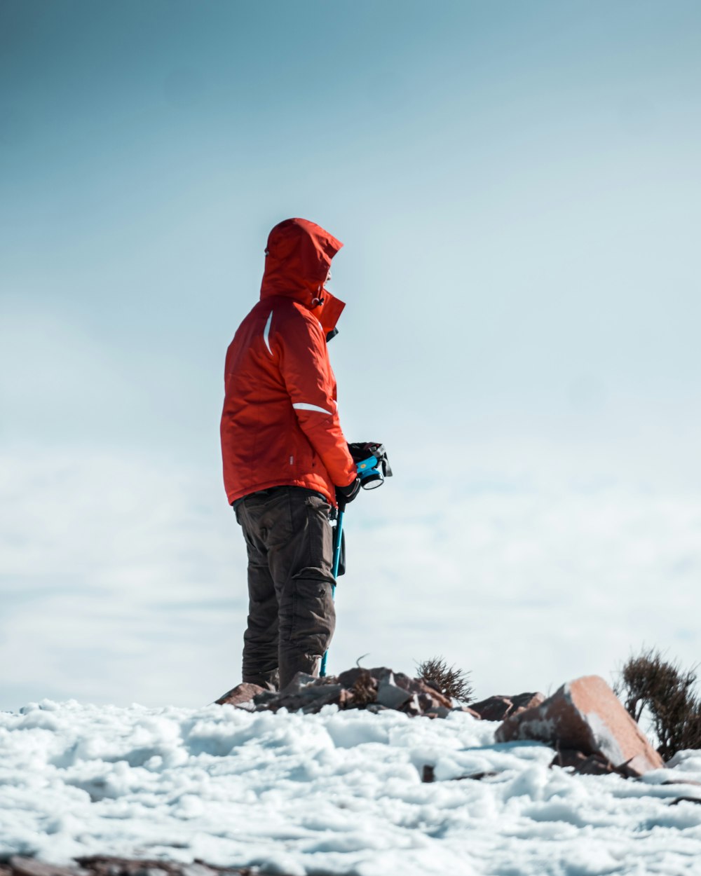 person in red hoodie and black pants standing on snow covered ground during daytime