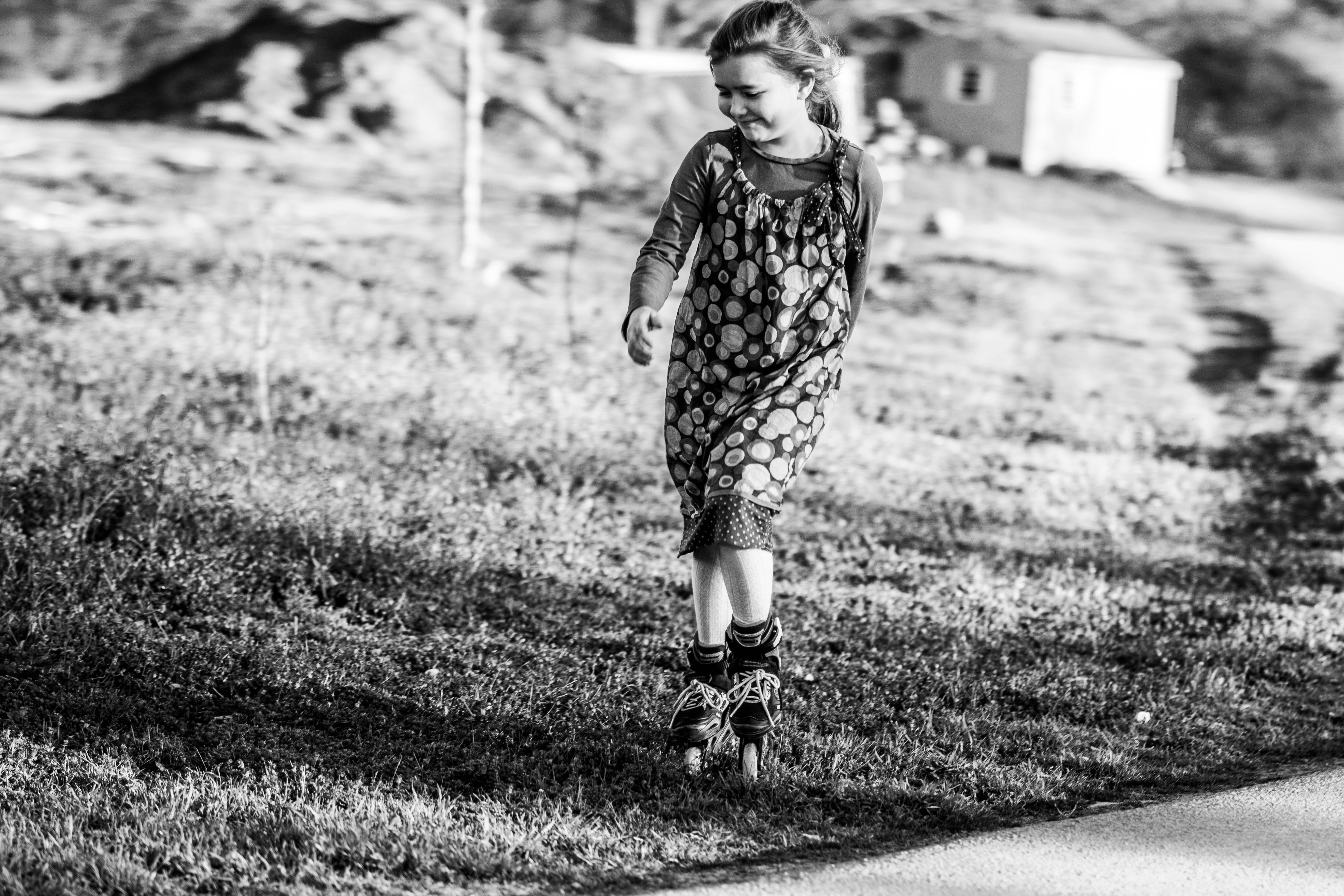 grayscale photo of girl in floral dress standing on grass field