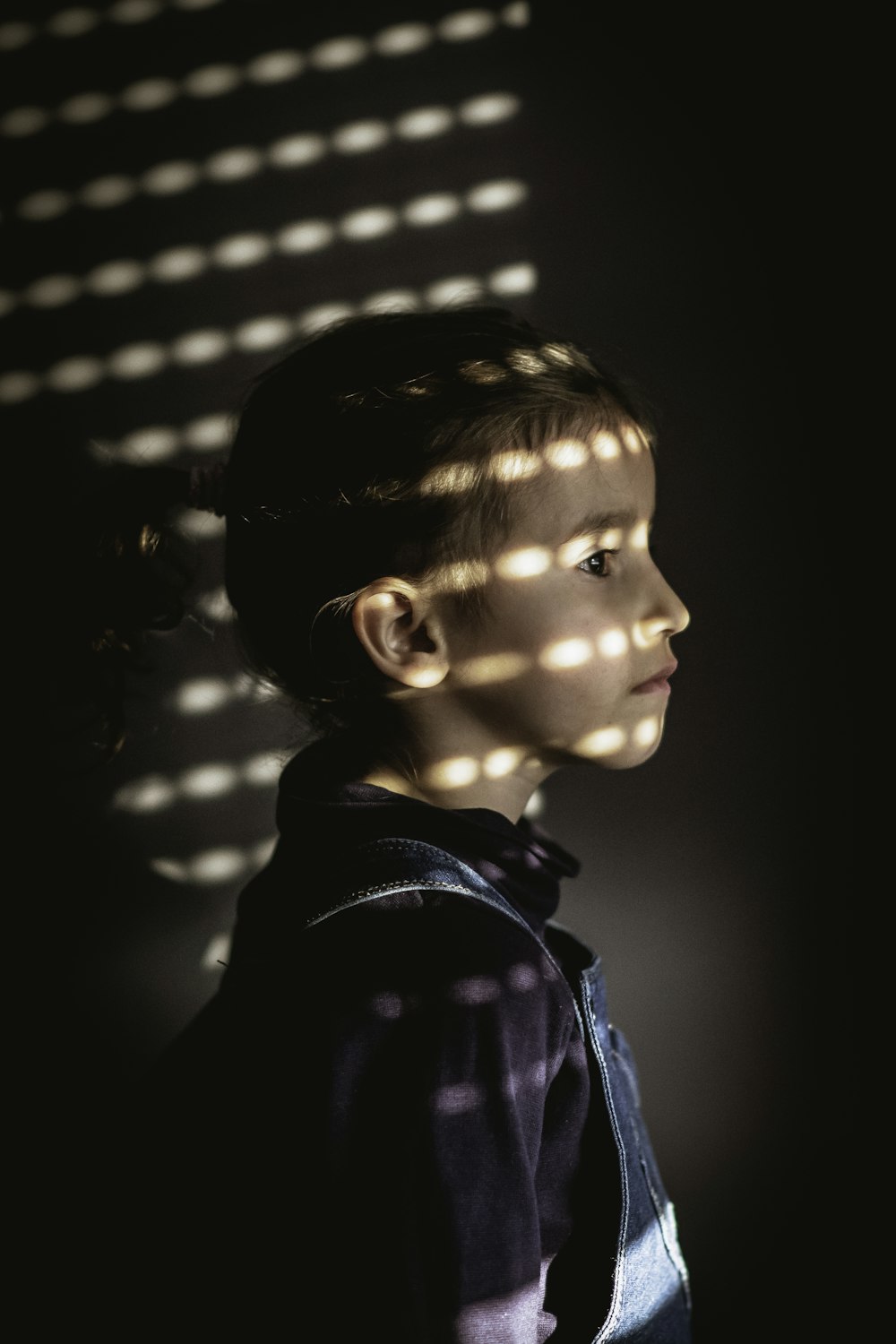 a young girl standing in front of a window with light coming through it