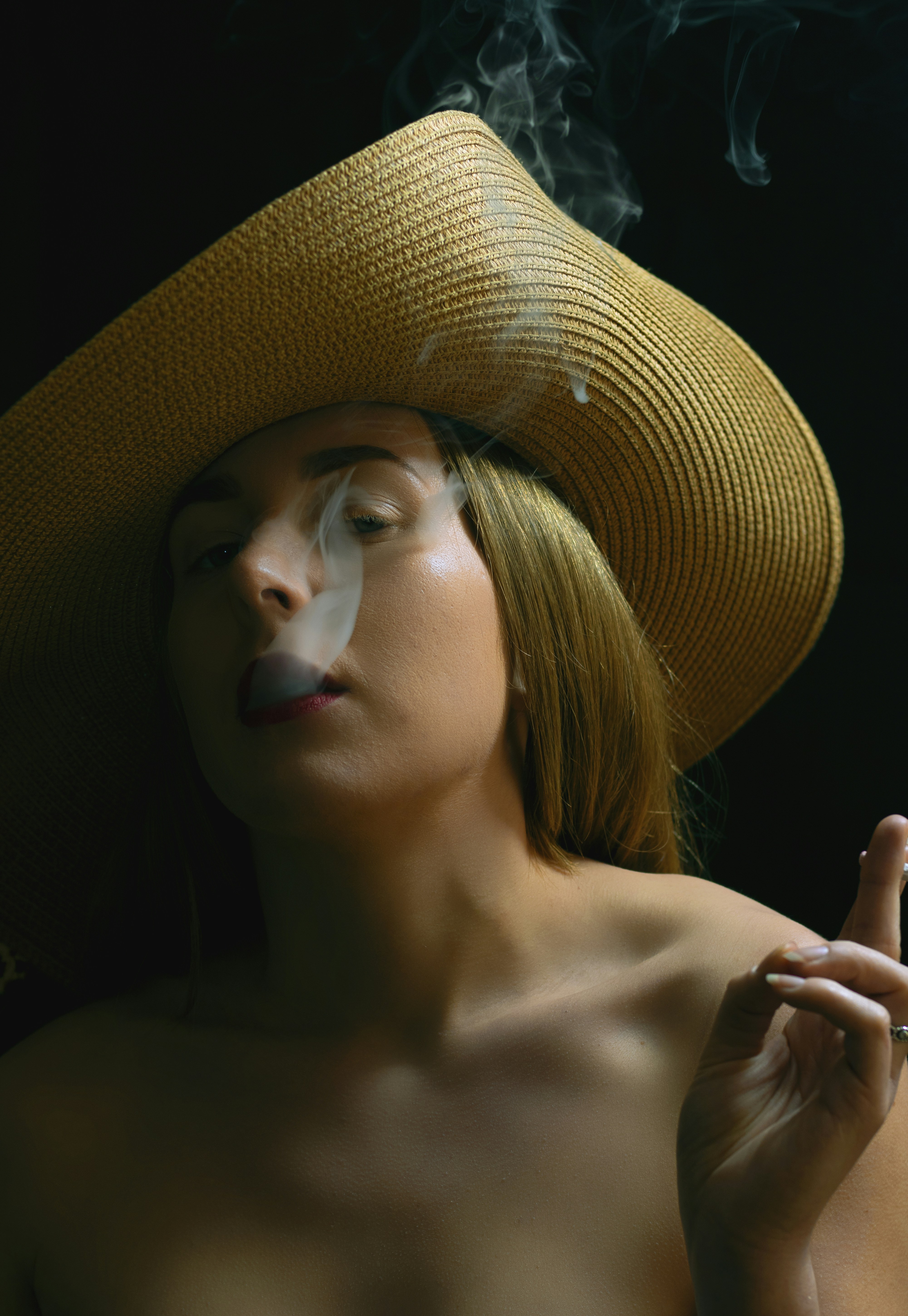 Girl smoking with floppy hat looking at camera side on