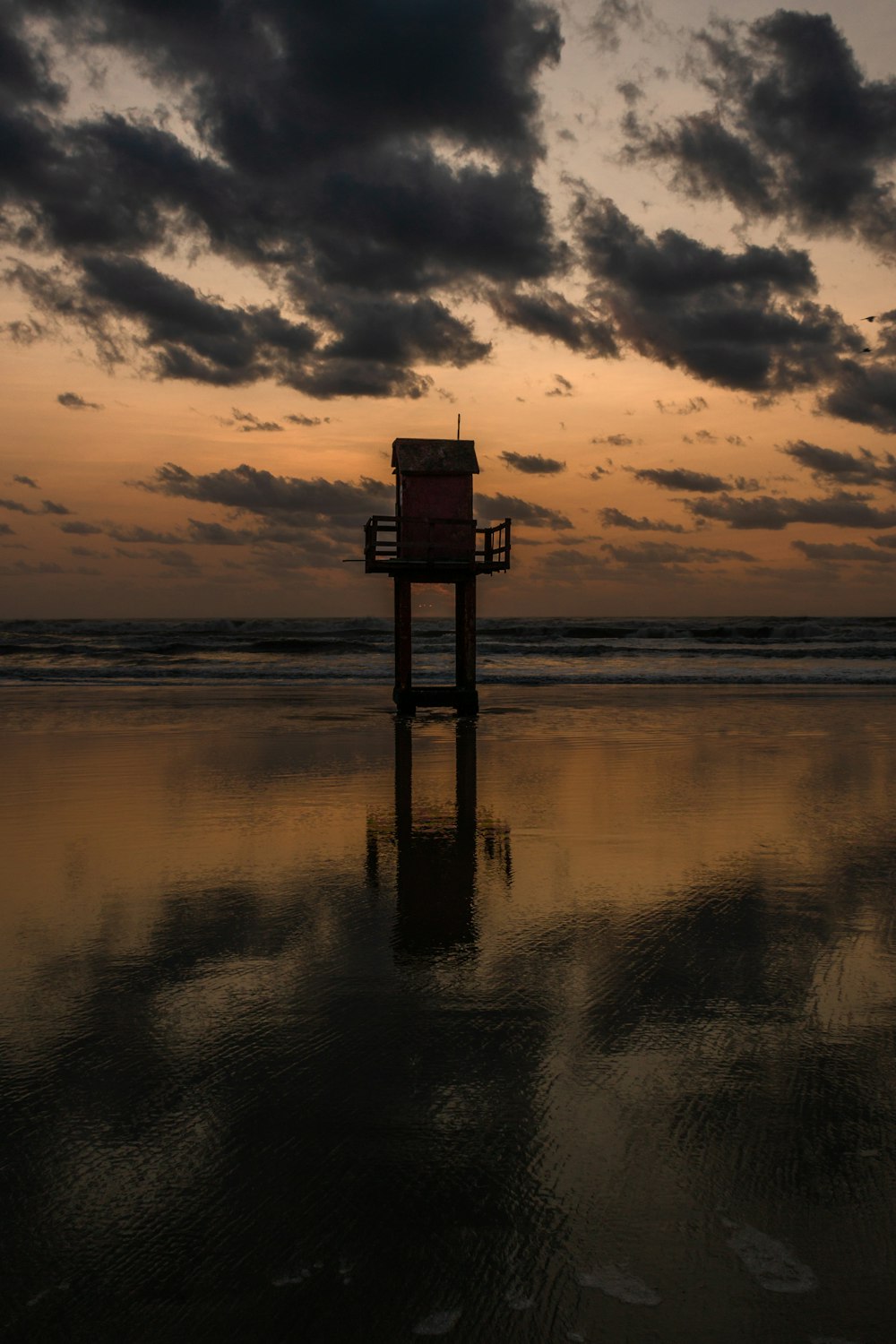 silhouette of wooden lifeguard tower on beach during sunset
