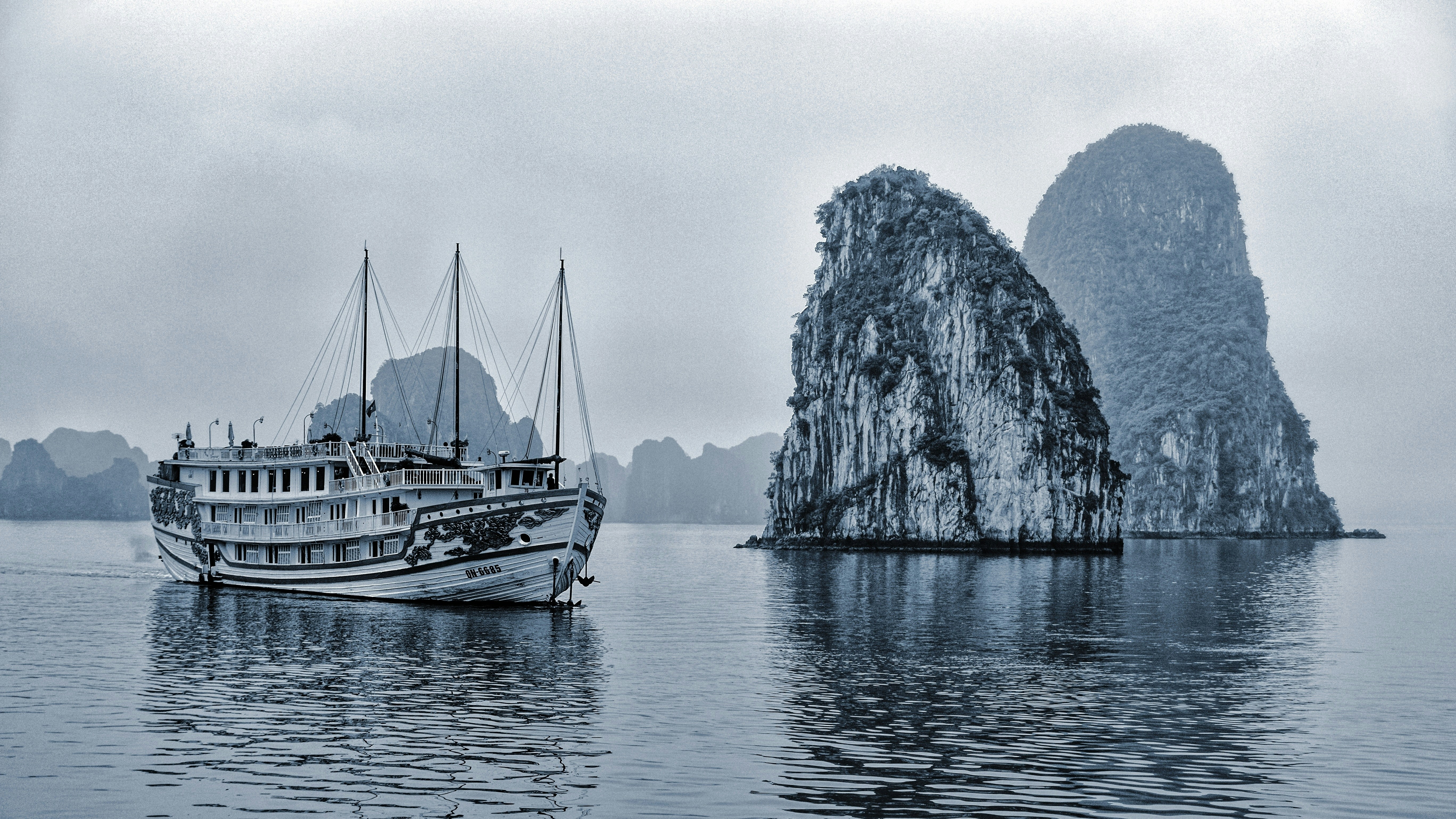 grayscale photo of boat on sea near mountain, Ship in Halong Bay