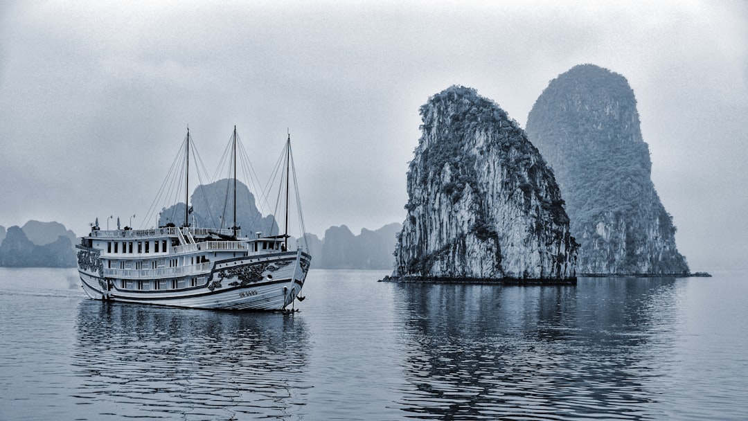 grayscale photo of boat on sea near mountain, Ship in Halong Bay