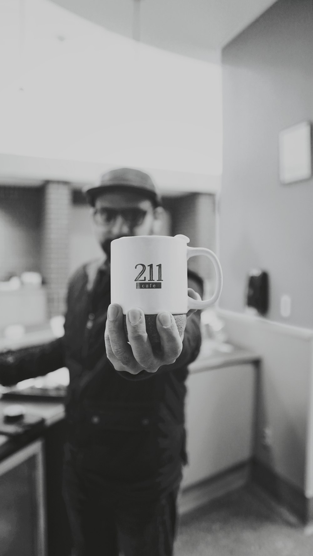 grayscale photo of man holding ceramic mug