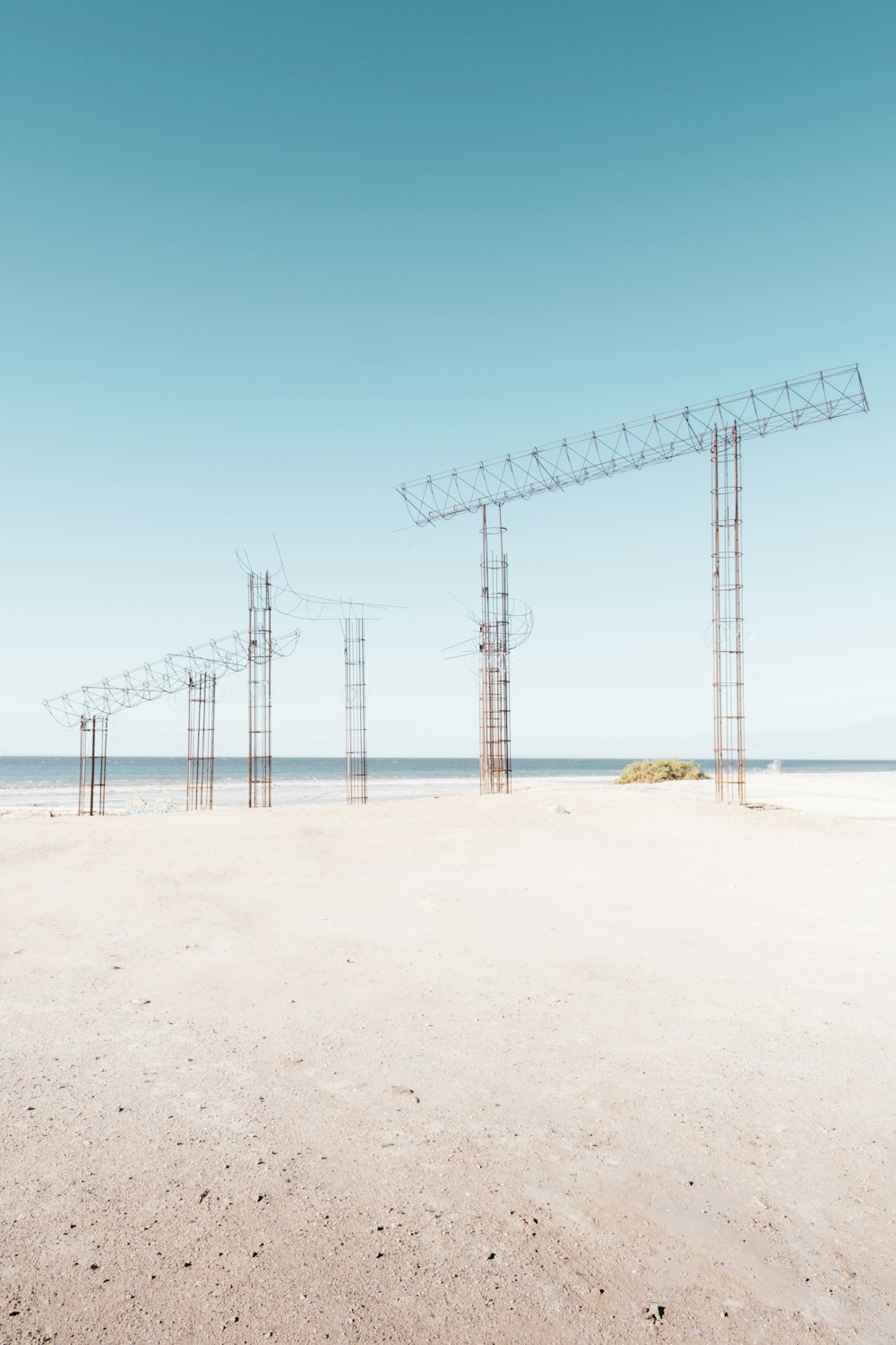 white metal tower on brown sand under blue sky during daytime