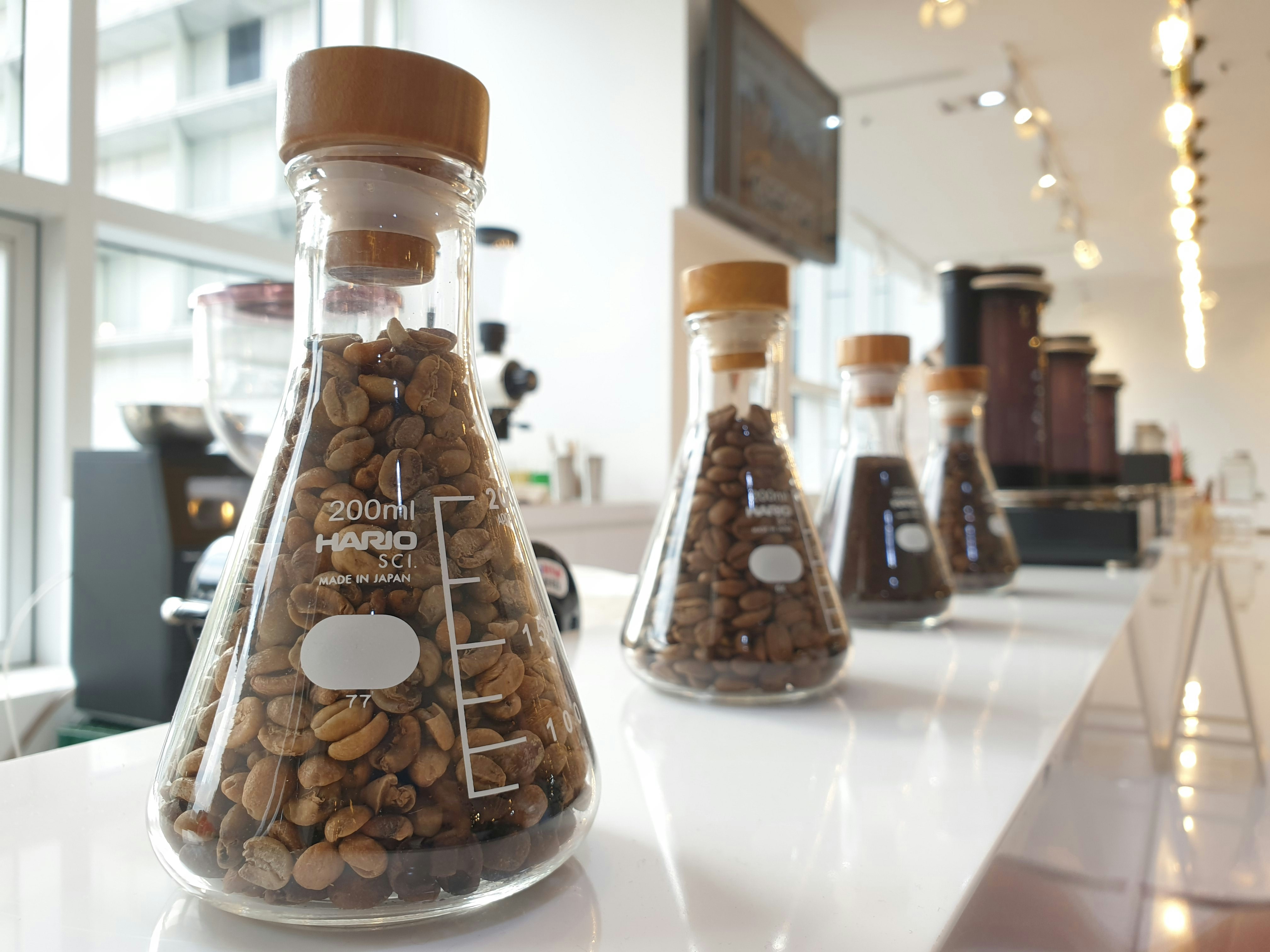 Coffee beans in glass jar on white lab counter, clean bright well-lit scientific environment
