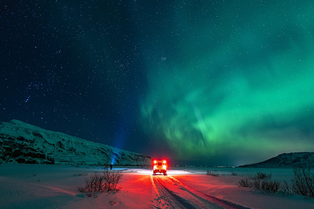a car driving down a snow covered road under a green light