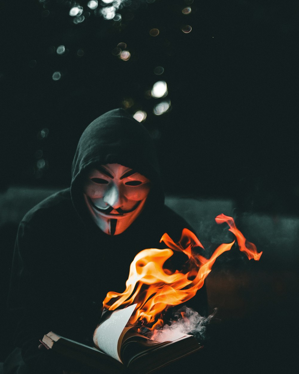person in black hoodie with orange flame in the background