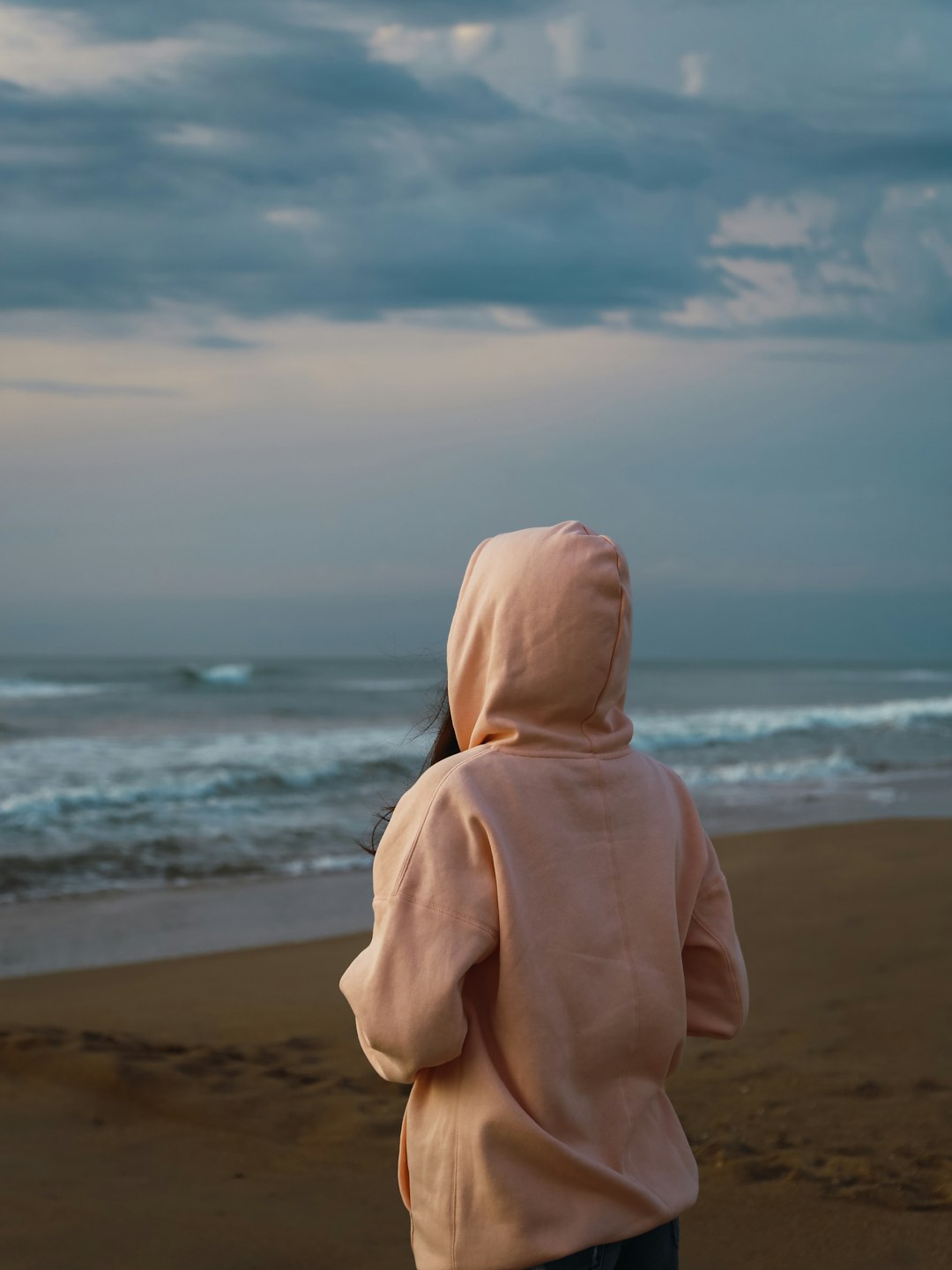 person in yellow hoodie standing on beach during daytime