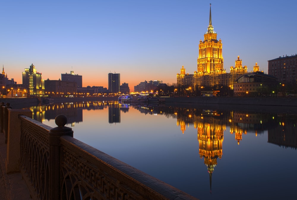 body of water near bridge and high rise buildings during night time