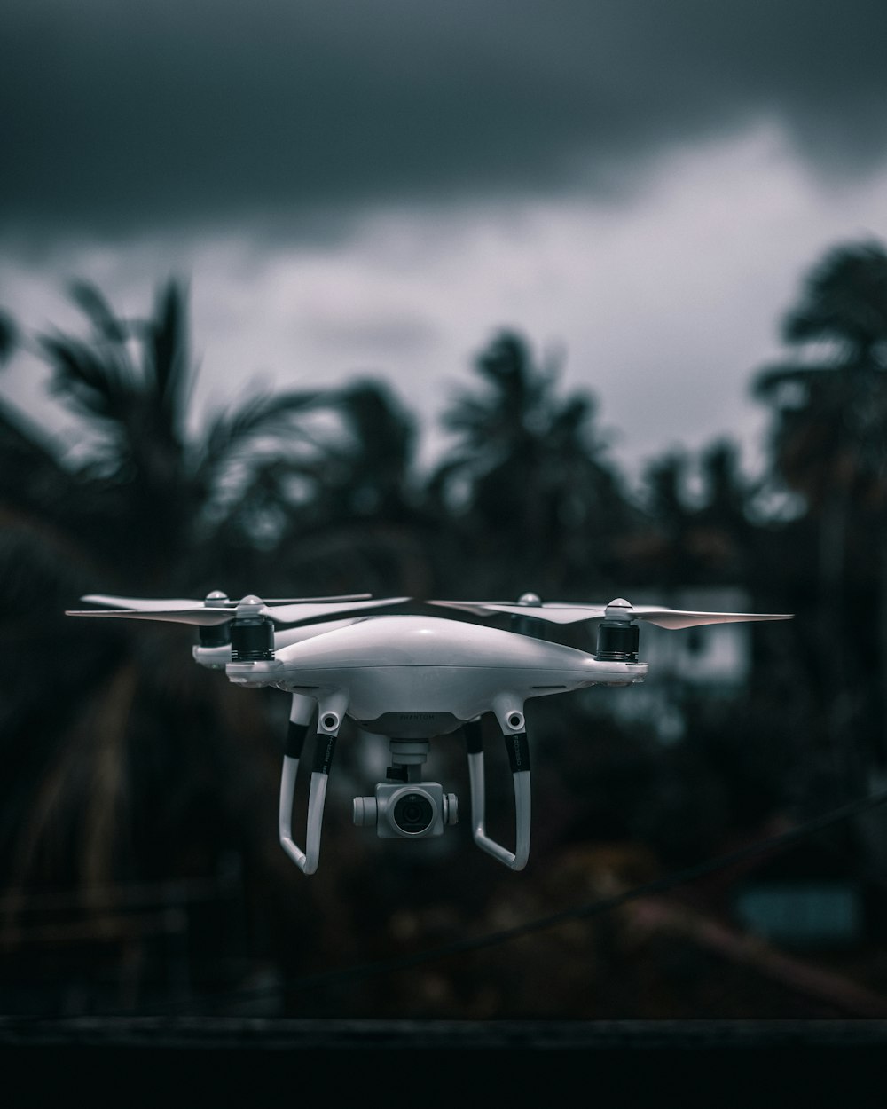 white drone flying in mid air during daytime