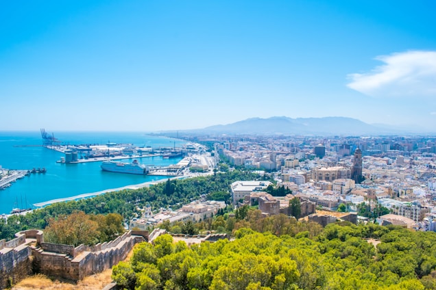 A panoramic view of Gujarat’s bustling port city with ships docked along the expansive coastline under a bright sky.