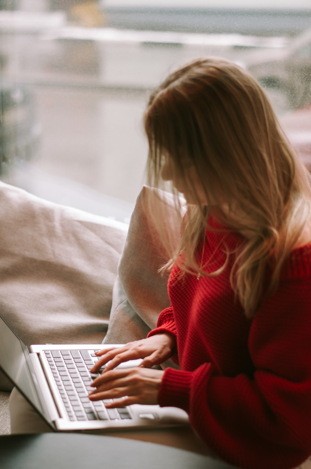 woman in red sweater using macbook air