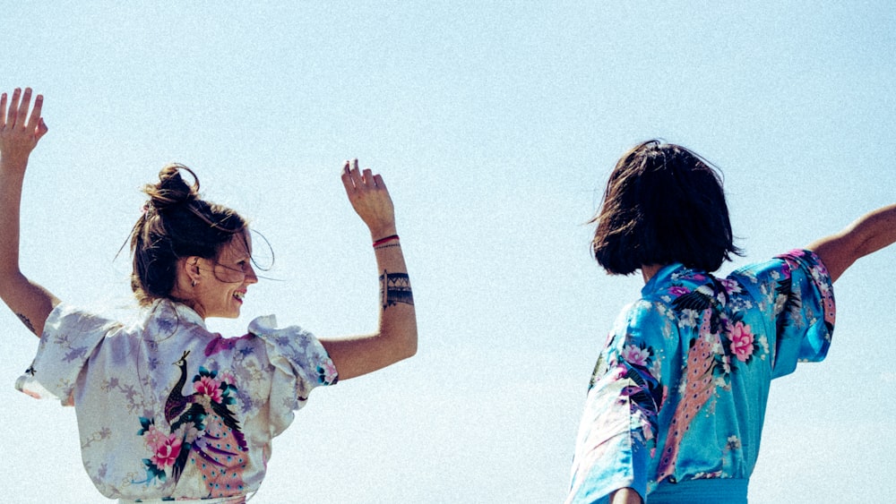 woman in white floral shirt raising her hands