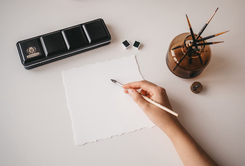 personne écrivant sur du papier blanc