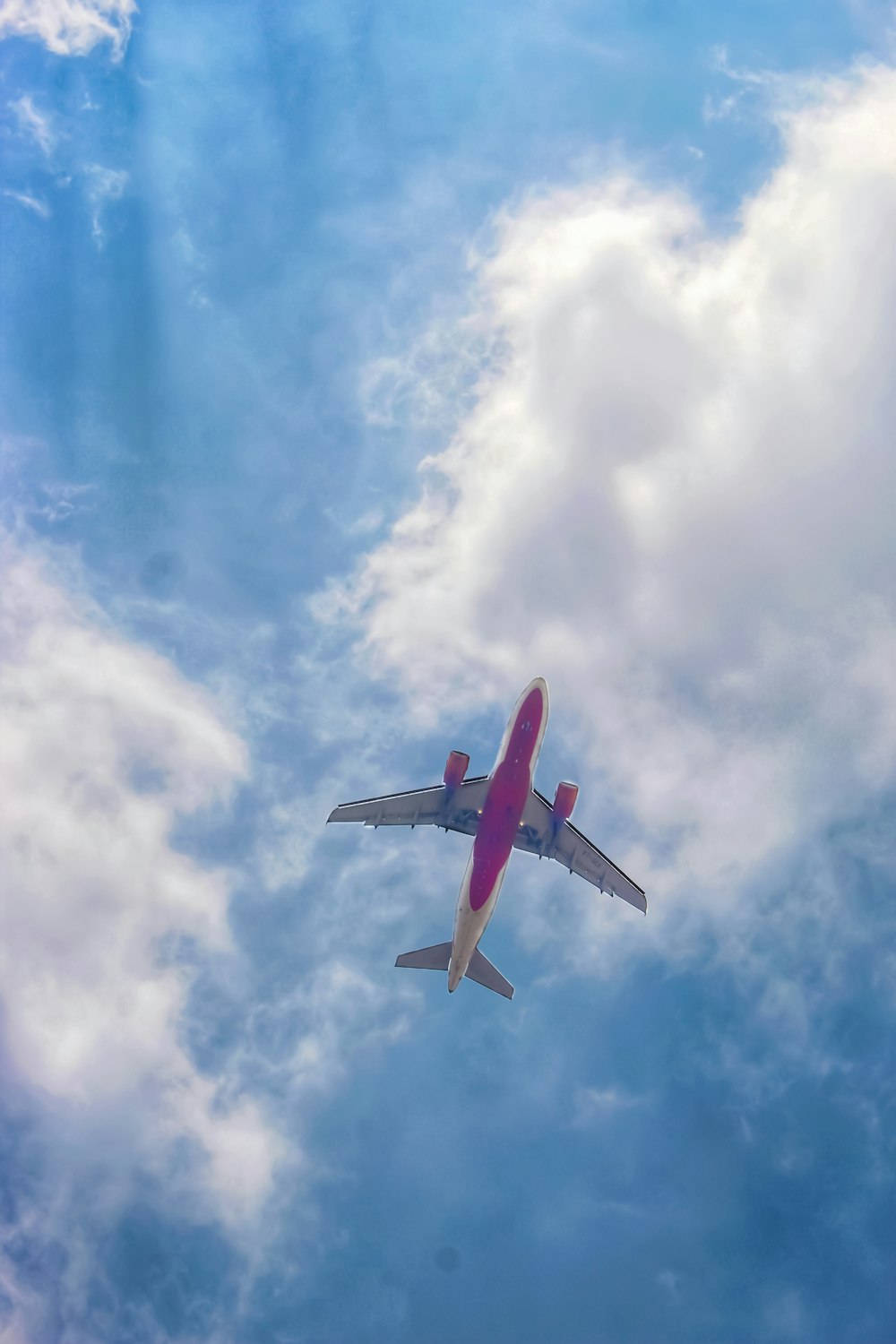 red and white airplane under blue sky and white clouds during daytime