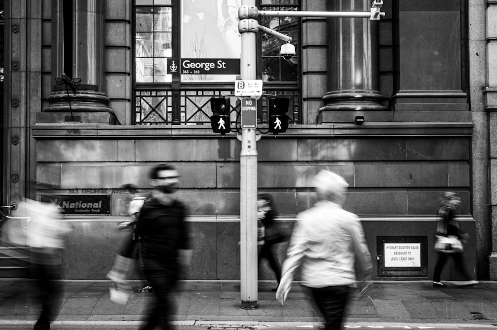 grayscale photo of man and woman standing near street light