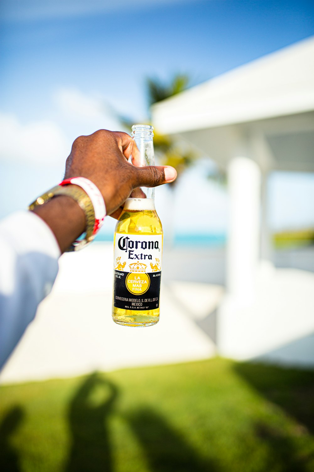 man in white dress shirt holding yellow and black labeled bottle during daytime