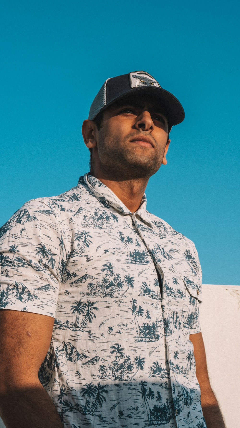 man in white and blue floral button up shirt wearing black cap