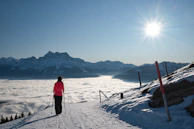 person in red jacket and black pants standing on snow covered ground during daytime