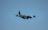 A military aircraft flying in a clear blue sky, showcasing its four propeller engines and robust design.