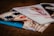 Three glossy fashion magazines are spread out on a surface. The cover of the left magazine features a close-up of a person wearing striped sunglasses and red lipstick. The center magazine shows a blurred image of a person in light-colored clothing, while the right magazine is partially visible and monochromatic.