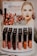 A display stand for Emani Vegan Cosmetics featuring Lip Shine Gloss with high impact colors. The poster includes an image of a woman with red lipstick and pomegranate seeds in the background. Below the poster, various shades of lip gloss are arranged in rows on a display.