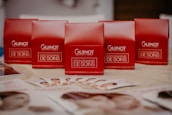 Several red boxes with 'Guinot Institut Paris' and 'Programme de Soins' written on them are arranged on a table. In the foreground, there are brochures displaying images of faces spread out on the table.
