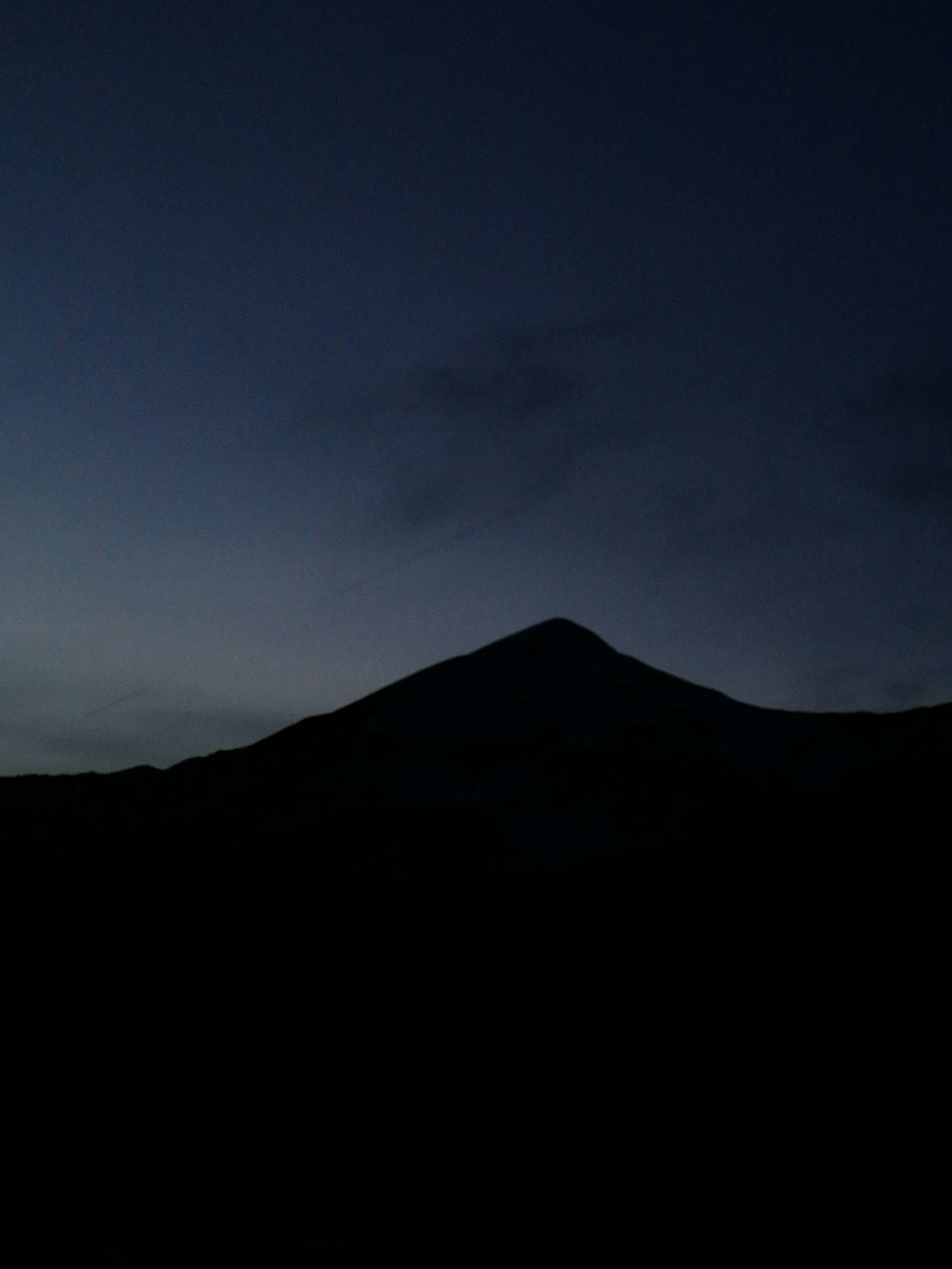 silhouette of mountain under blue sky during night time