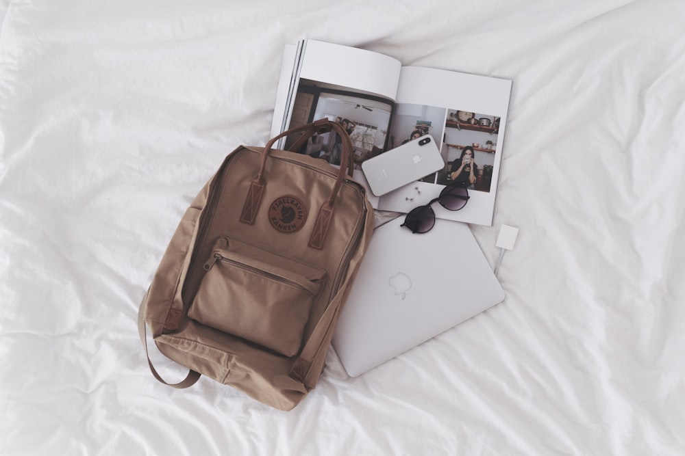 silver ipad beside brown leather handbag