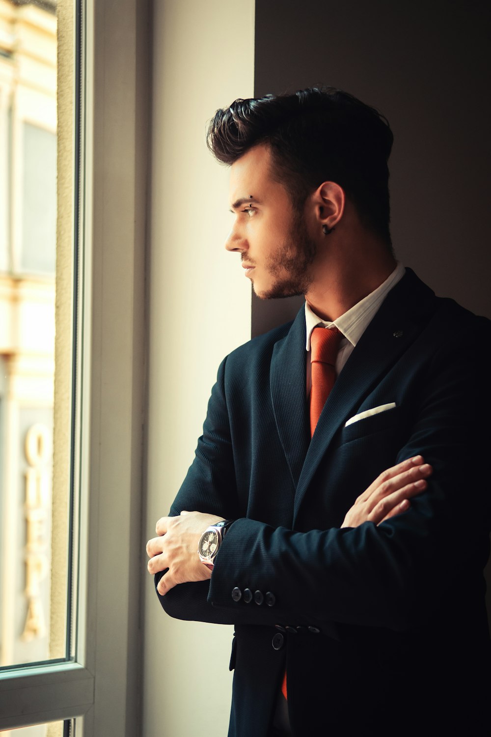 man in blue suit jacket standing near window