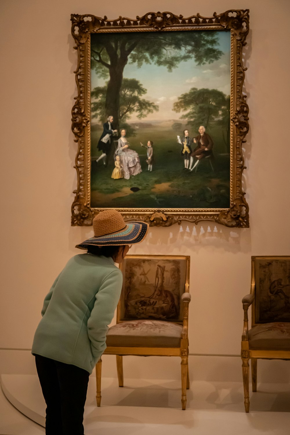 person in white shirt and brown hat sitting on brown wooden armchair