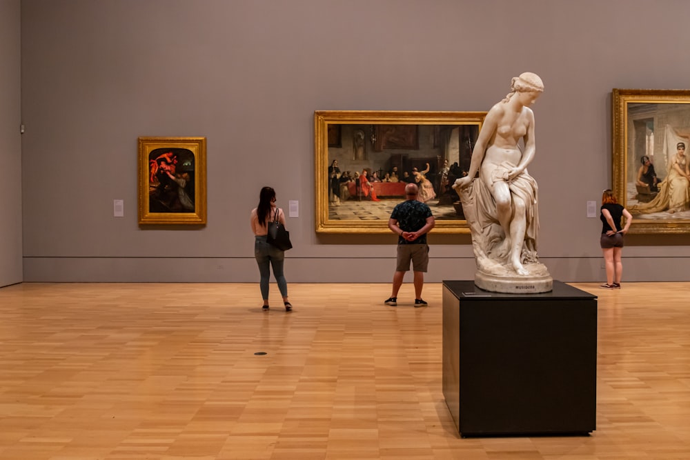 mulher na camisa preta da manga comprida que está de pé perto da estátua branca