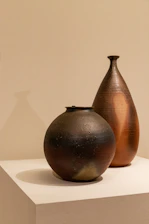 Close-up of a smooth, matte ceramic vessel with sharp, clean lines against a pure white background.