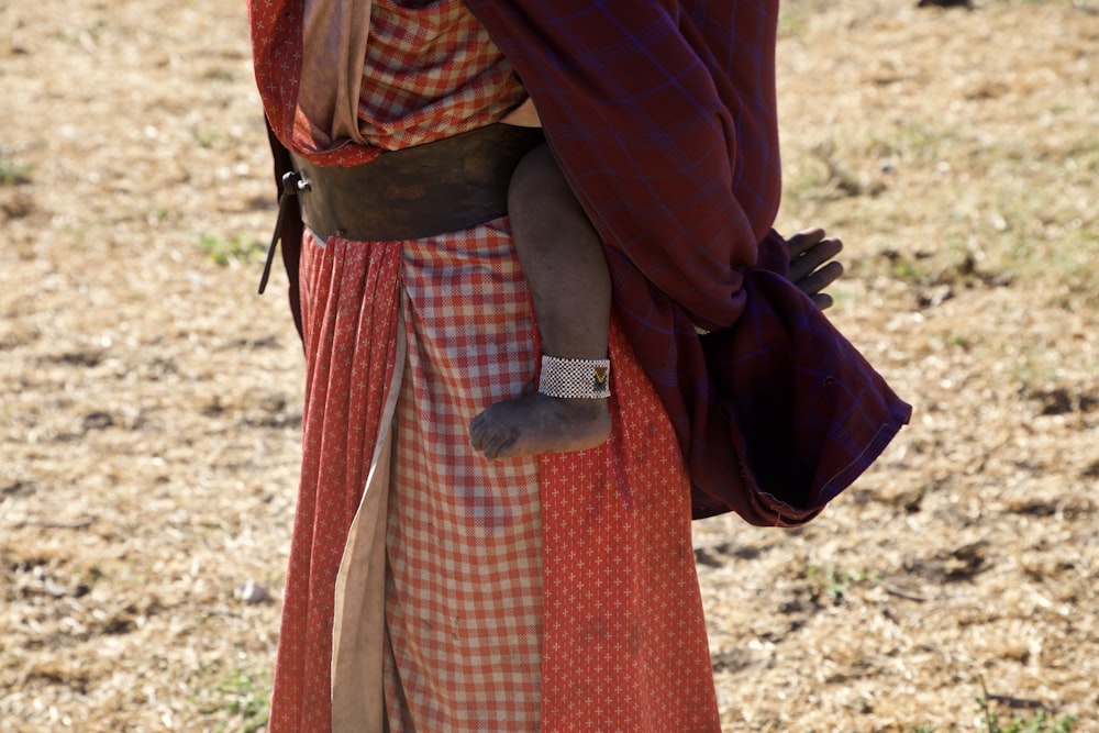 Femme en robe rouge et blanche portant des bottes en cuir noir