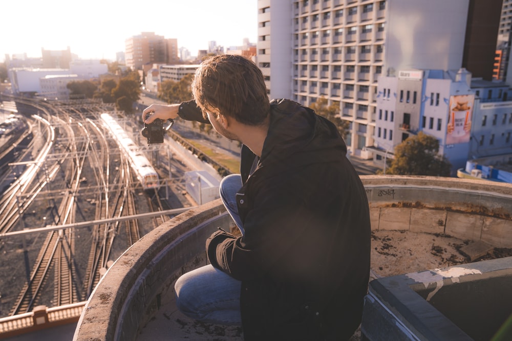 man in black hoodie standing on top of building during daytime