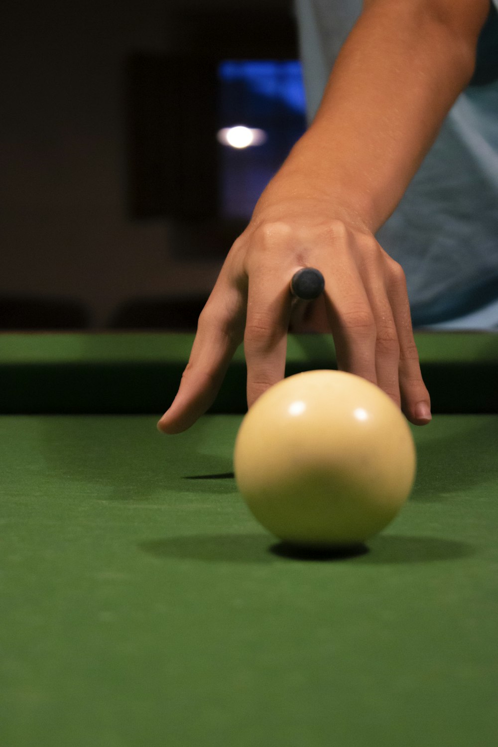 person holding yellow ball on green billiard table